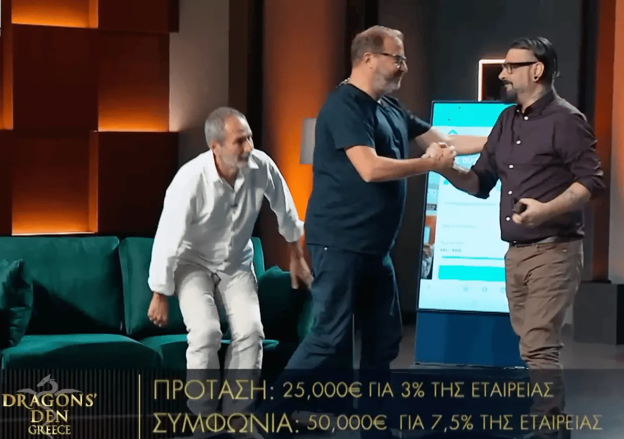 Shaking hands with an investor on the Dragons' Den Greece stage under a caption reading 50,000 euro for 7.5 percent