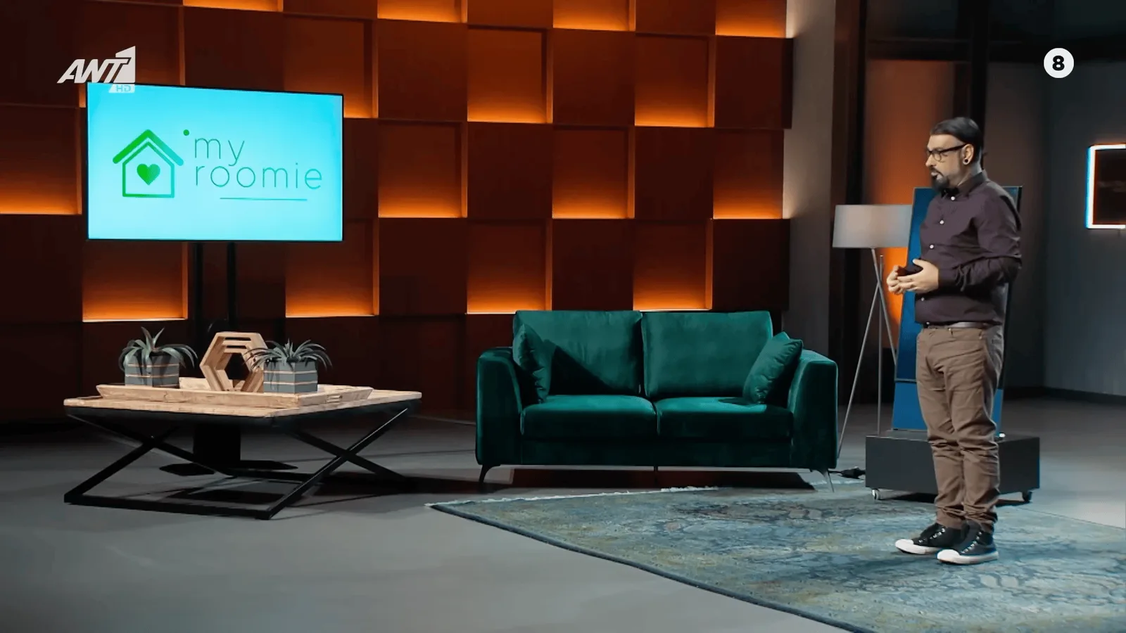 Pitching MyRoomie on the Dragons' Den Greece stage, the company logo on the screen behind